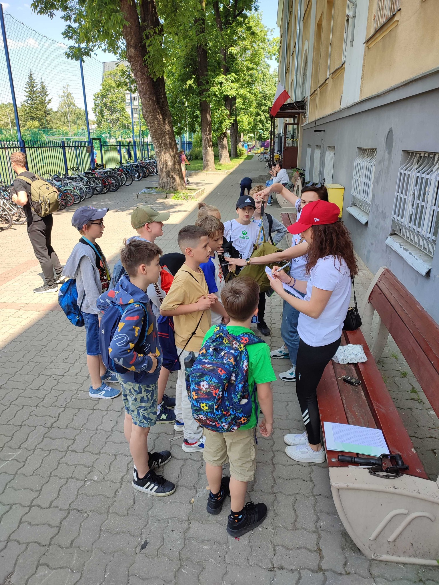 Fizjoterapeutka rozmawia z grupą dzieci przy placówce edukacyjnej